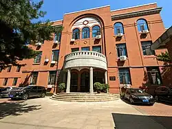 Front wiew of the schools entrance featuring a curved balcony supported by pillars