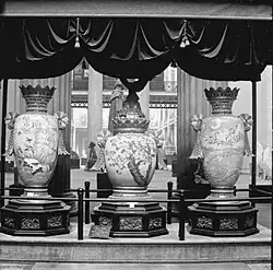 The three vases in a display area with a plaque