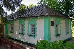 Photograph of a white and green house surrounded by trees