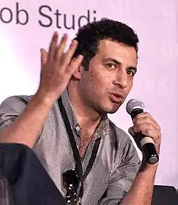 Aamir Bashir gesturing and speaking into a microphone