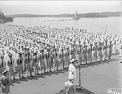 Black and white photo of men in military uniforms on the deck of an aircraft carrier