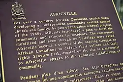Text reads "For over a century African Canadians settled here, developing an independent community centred around church and family. As part of the urban renewal projects of the 1960s, officials introduced a plan to level the community and relocate its residents. The community mobilized and even though no buildings were saved, Africville became a symbol of the ongoing struggle by African Canadians to defend their culture and their rights. Seaview Park, created on the site as a memorial to Africville, speaks to the enduring significance of community."