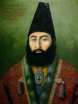 Oil on canvas painting of a bearded man wearing a long cap and ornate clothing, on the top left is Persian text