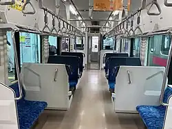 The interior of a train carriage with blue fabric and vinyl seats and large windows