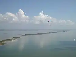 Aerial photograph of a bay and islands with a paramotoring figure
