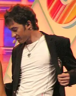 A shot of Arsenie Todiraș, sporting a black blazer on top of a white shirt in front of a multicoloured backdrop.