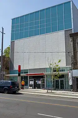 A photo of the largely completed secondary entrance to Avenue station. It is a modern, white building with glass panelling.