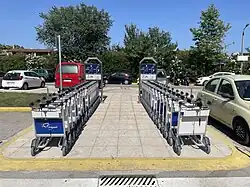 Passenger-operated baggage trolleys stacked into a trolley corral at a port passenger terminal in Greece