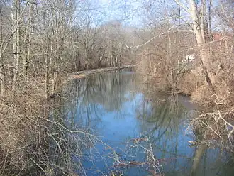 Leafless trees overhang a water channel that is uniformly about 25 feet (7.6 meters) wide.