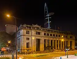 The Saigon bank's building at night, with Bitexco Financial Tower in background