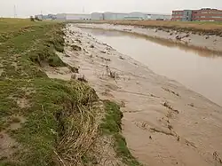 A narrow river with steep mudflats on its banks