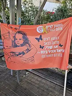 A banner with a painting of Shiri and the children on display on the day of their funeral