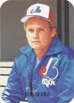 A man in a blue jacket and white baseball cap