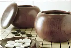 Image 22An example of single-convex stones and Go Seigen bowls. These particular stones are made of Yunzi material, and the bowls of jujube wood. (from Go (game))