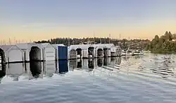 A dusk picture of a row of boat sheds from the Bremerton Yacht Club, taken from water level.