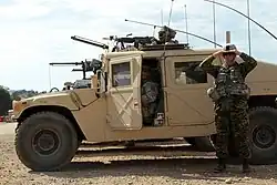 A soldier shades his eyes next to a vehicle