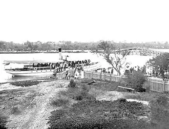 Passengers leaving the Silver Star river steamer ferry at Coffee Point (site of the South of Perth Yacht Club), with the old Canning Bridge in the background,  1906