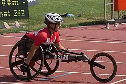 White woman with a red and white top in a black wheelchair.
