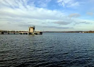 A large lake with a jetty and a water tower