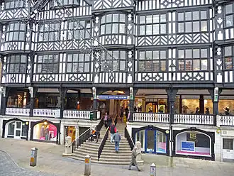 There are shops on the street level with wide steps leading to the first floor where there on more shops on the Rows. Above this are 2+ storeys in black-and-white architecture.