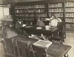 Black-and-white photo of three children in a room, one of them looking through a stereopticon