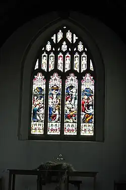 Picture of the stained glass window gifted by Hill to Axbridge parish church after its restoration in 1887. Four lights are shown representing Nativity, Crucifixion, Resurrection, and Feed my Lambs