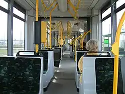 View along entirely flat tram aisle. The seats either side are a mixture of single seats and pairs.