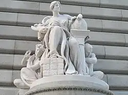 Marble statue of a seated woman leaning on a globe
