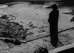 A man only visible as an outline stands overlooking a dirty sump.