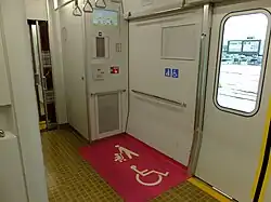 Wheelchair space at the end of a Japanese train with the floor painted pink to improve visibility
