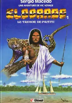 A man holds out a mystical object with a jaguar behind him. Beneath him, there is an ocean. Reads at the top Sergio Macedo, Une aventure de Vic Voyage, below Eldorado 1: Le tresor de Paititi
