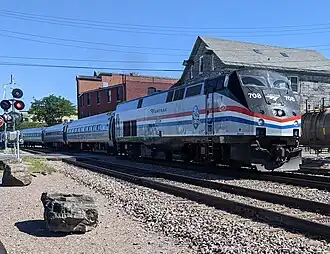 A passenger train with a diesel locomotive at a grade crossing