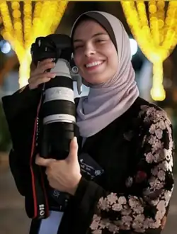 Hassouna smiling and holding a camera