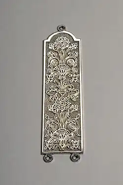 Silver fingerplate with a stylised flower design.
