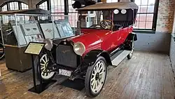 A red-colored, old-fashioned car with four seats and black-colored fittings