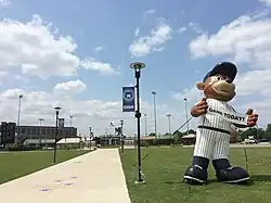 Walkway leading to Four Winds Field at Coveleski Stadium, pictured in July 2015. There is an inflatable display of the South Bend Cubs mascot, Stu, holding a sign advertising a game to be played that day.