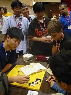 Image 2Three Japanese professional Go players observe some younger amateurs as they dissect a life and death problem in the corner of the board, at the US Go Congress in Houston, Texas, 2003. (from Go (game))
