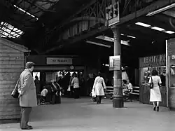 The view inside the vaulted ceiling of a metal shed-like structure, bustling with people