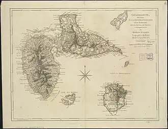Beige paper with a hand drawn map of Guadeloupe, with the small island of Marie-Galante to the southeast, and the small island of La Désirade to the northeast. A compass rose is drawn in the center.