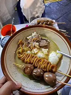 Gultik, sliced beef gulai served with rice and satay skewers