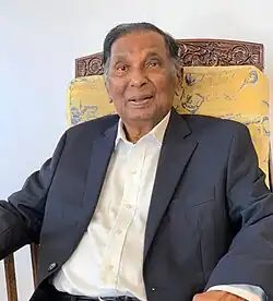 A Man on a black suit sitting on a chair