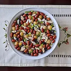 A colorful bowl of mixed dried fruits viewed from above, sitting on a flowered cloth