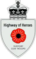 A Highway of Heroes reassurance marker with a red poppy flower in place of a number. Above that is the text Highway of Heroes, and below it SUPPORT OUR TROOPS.