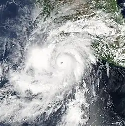 A photograph of a powerful hurricane just off the Pacific coast of Mexico, with some of its northern rainbands spreading over land. The hurricane has an oblong shape, oriented from the lower-left to the upper-right.