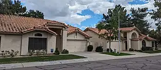 One-story patio homes with red roofs surrounded by mature landscaping
