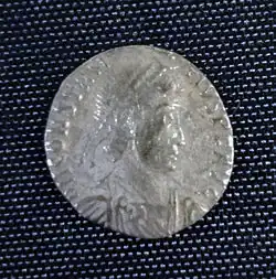 A smaller silver coin in the centre a head - still a fairly round coin but the inscription is not intact and there is no space between it and the rim