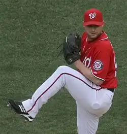 A man in a red baseball jersey and cap and white pants