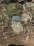 Bronze plaque embedded in the rock face next to the tombstone for James Jeffrey Roche in Holyhood Cemetery