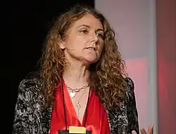 Woman with mid-length dark curly hair looks off to the right