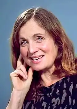 White caucasian woman around 57 years old, long brown hair, resting face on right hand